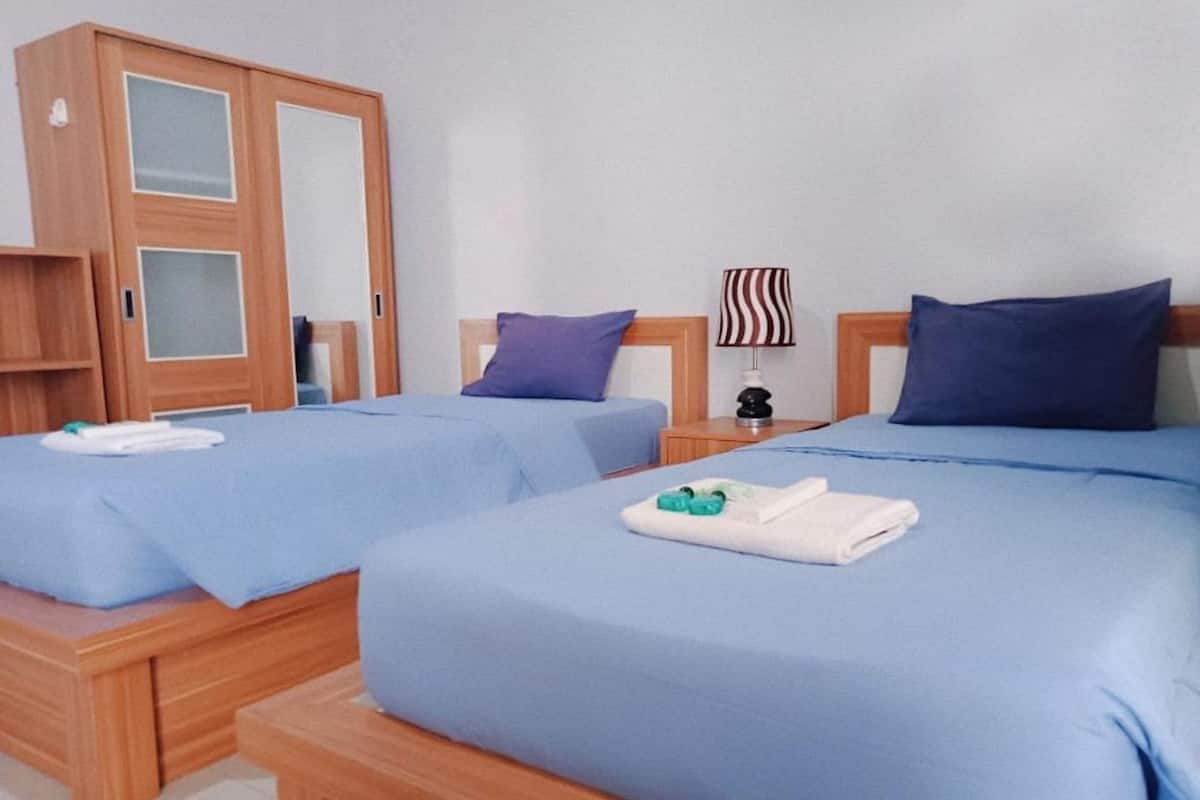 A hotel room with two beds, wooden headboards, and a wardrobe with glass doors.