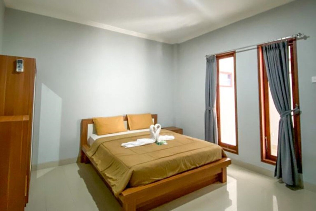 A spacious bedroom with a large bed, a wardrobe, and a window with curtains.