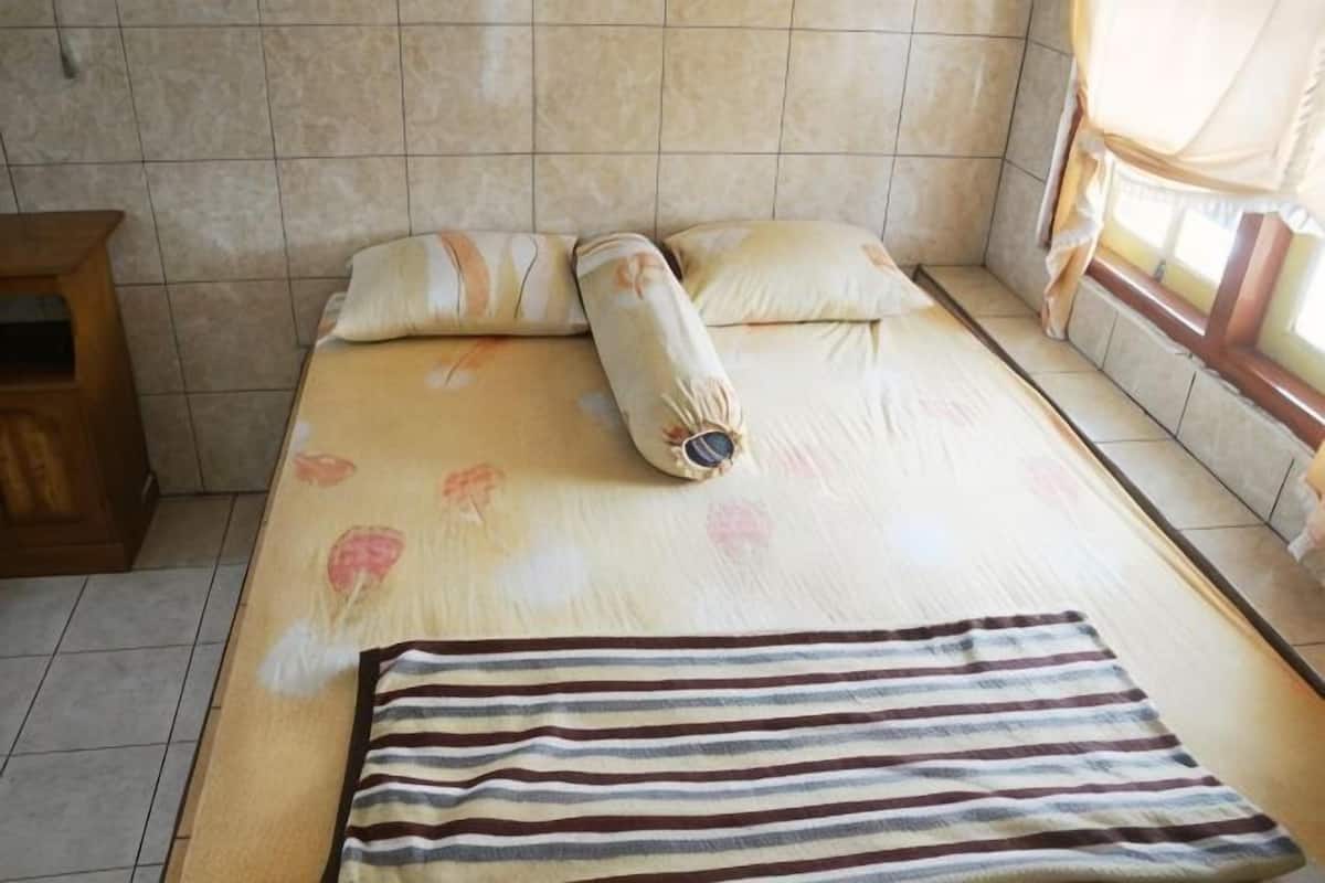 Una cama con una colcha floral, una manta a rayas y una almohada.