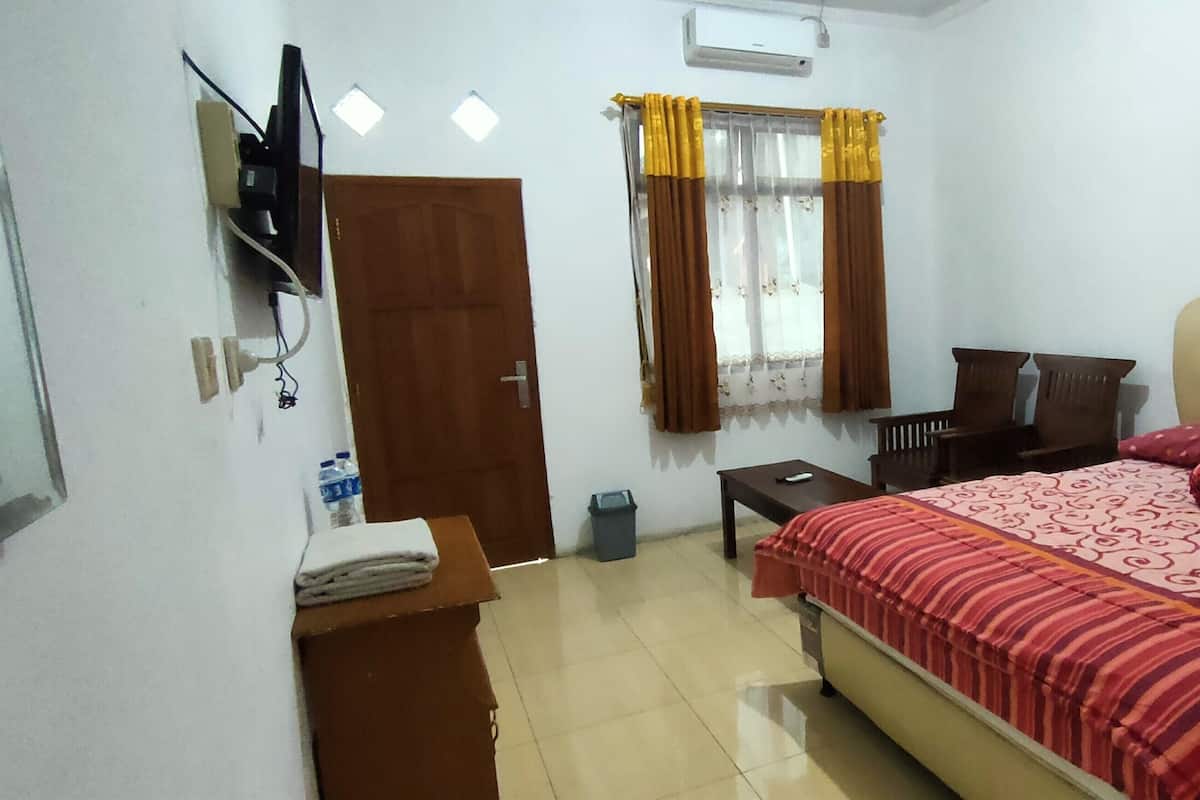Un dormitorio con cama, escritorio, silla, televisor y armario.
