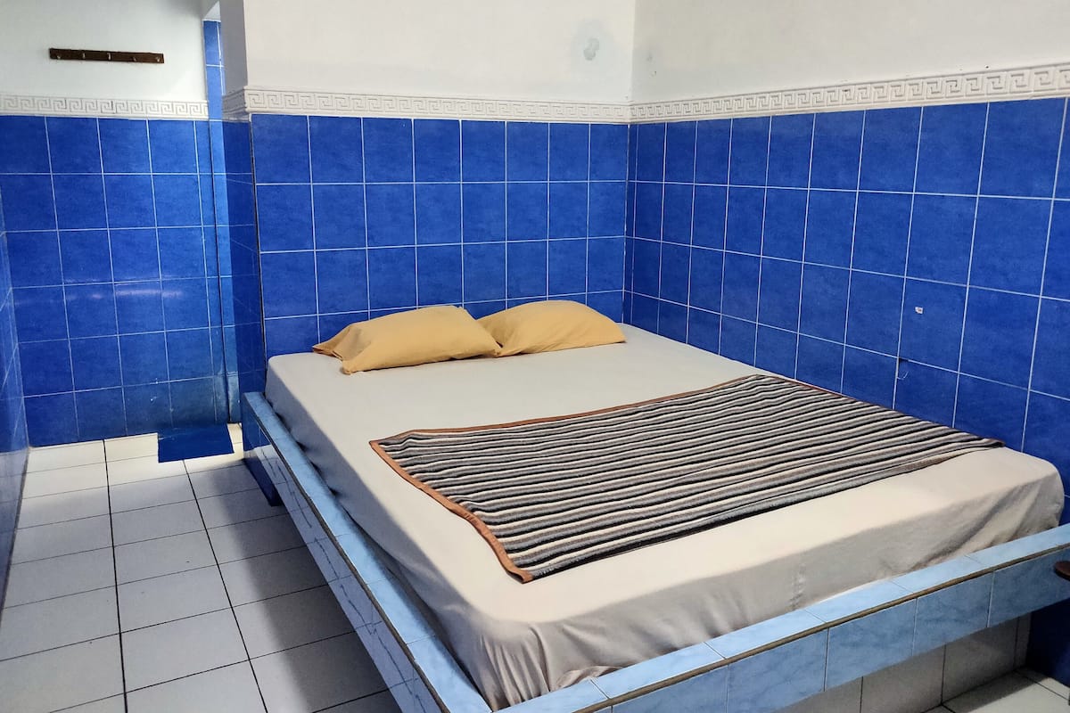 Una habitación con cama, paredes de azulejos azules y techo blanco.