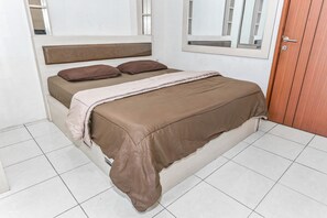 Uma cama com cabeceira, duas almofadas e um cobertor.