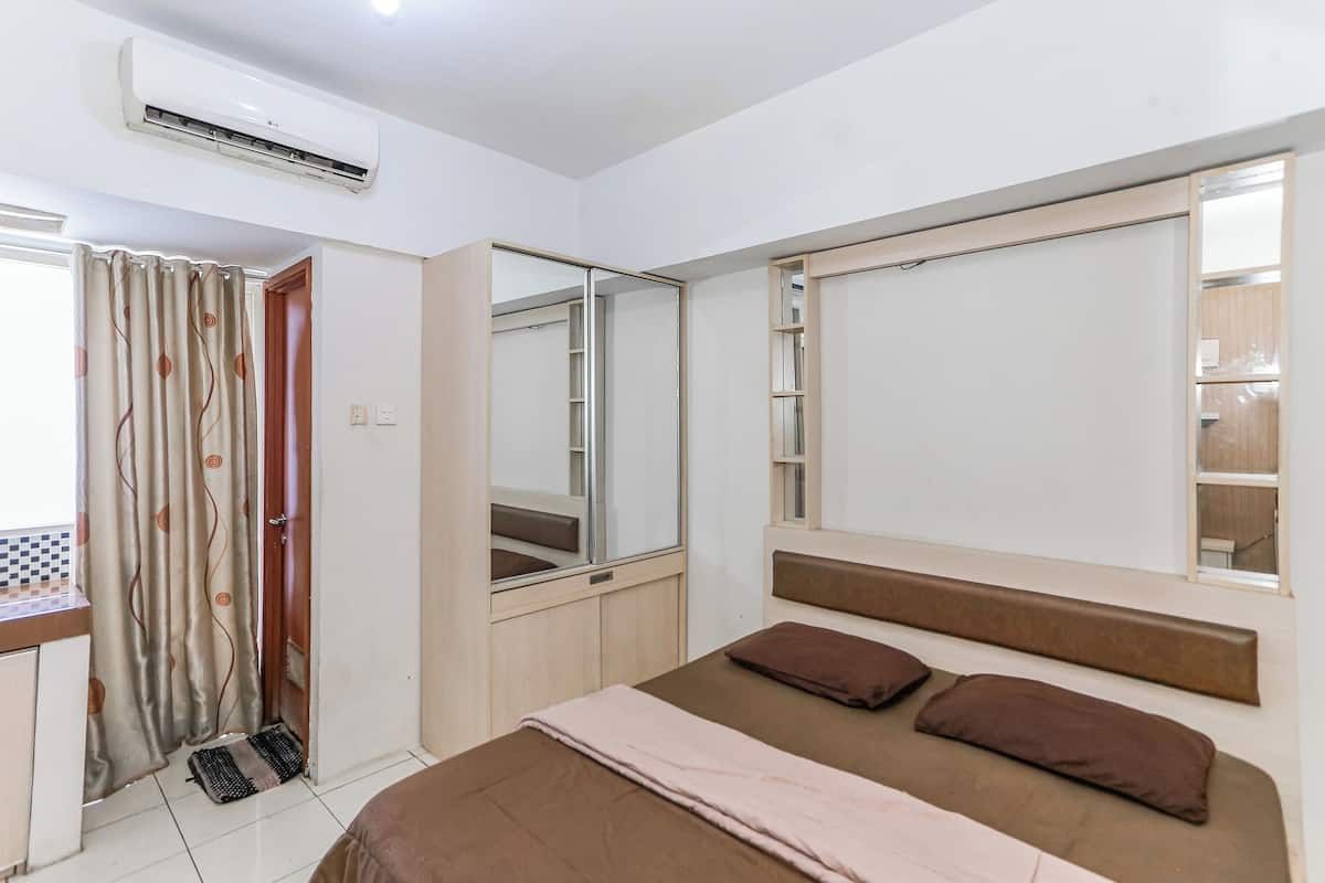 A bedroom with a bed, a mirror, a wardrobe, and an air conditioning unit.