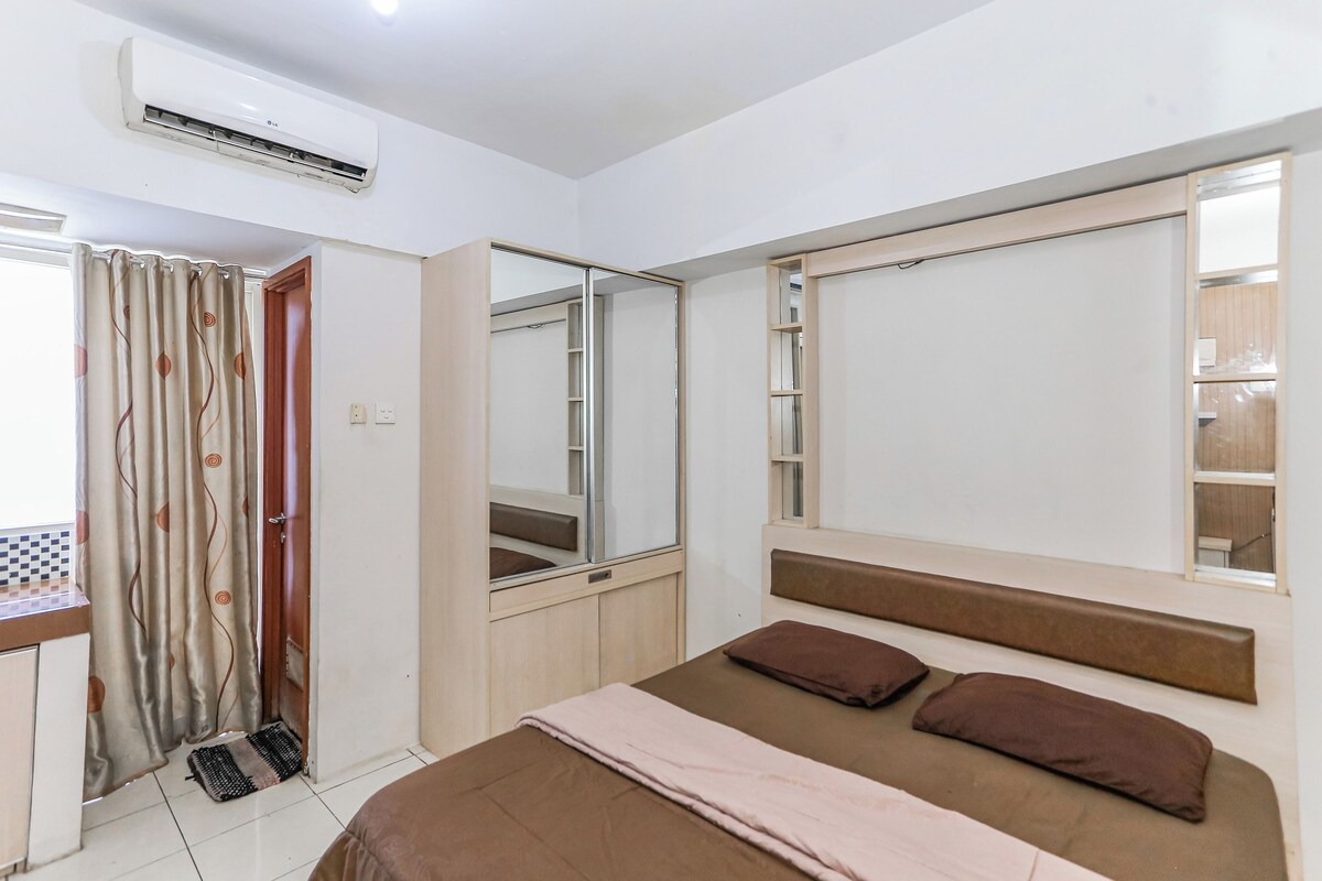 A bedroom with a bed, a mirror, a wardrobe, and an air conditioning unit.