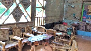 A room with bamboo furniture, including chairs and a table, with a view of greenery outside. - Penginapan Puncak DP (Berastagi)
