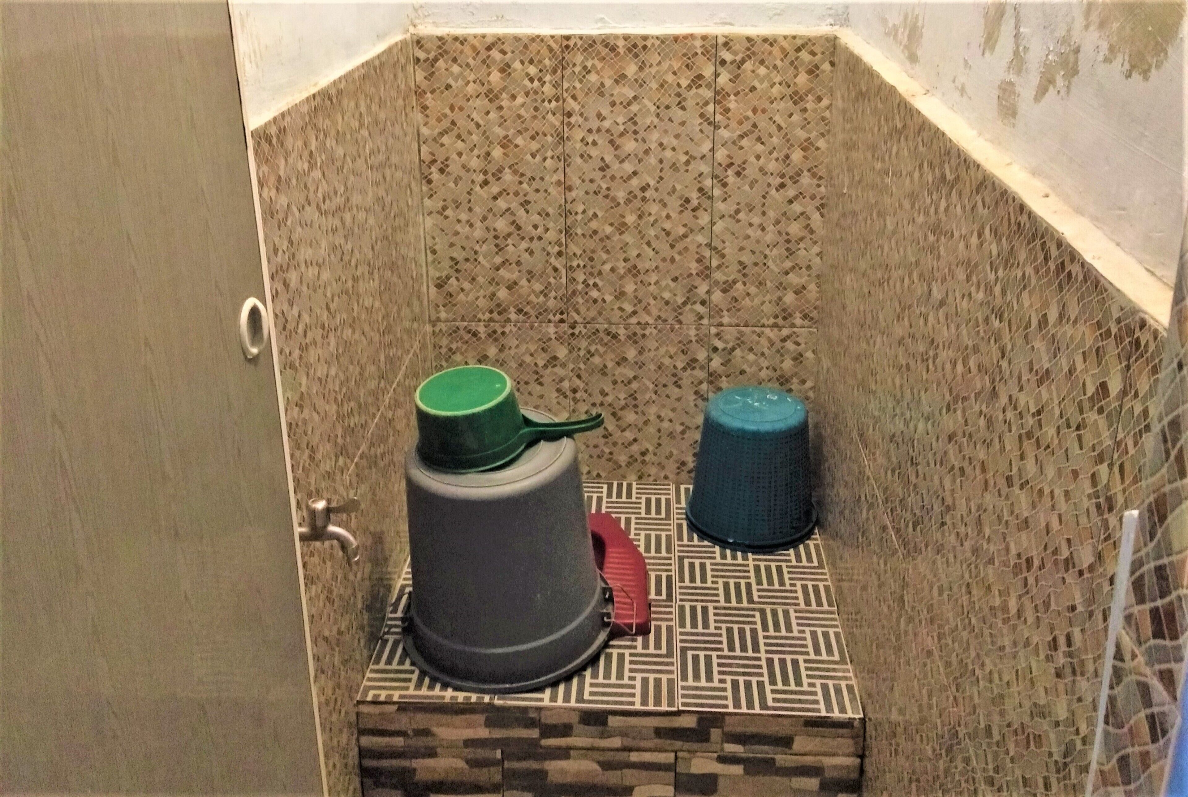 A bathroom with patterned tiles, a shower area, and two water containers.