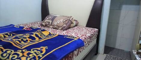 Una cama con colcha estampada, almohadas y cabecero.