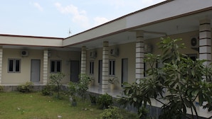 A building with a covered outdoor area, columns, and potted plants. - Penginapan Transit Tomato (Medan)