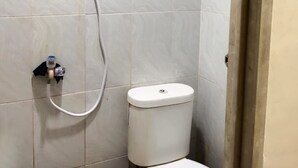 Une petite salle de bain comprenant des toilettes, une douche et un robinet fixé au mur.