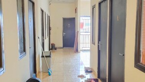 Un couloir carrelé, avec des portes de chaque côté et un distributeur d’eau sur la gauche.