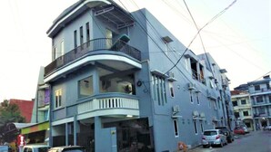 A multi-story residential building with balconies, a gated entrance, and parked cars. - Siwalankerto F7 (Surabaya)