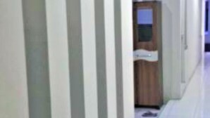 A hallway with a wooden door and a white wall. - Siwalankerto F7 (Surabaya)