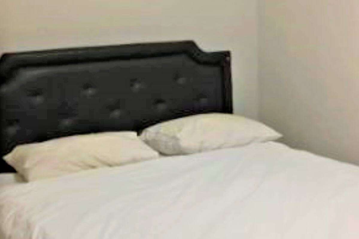 Uma cama com cabeceira escura e roupa de cama branca.