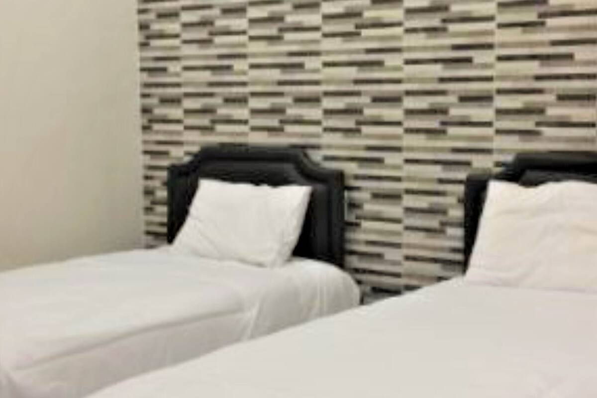 Quarto de hotel com duas camas de solteiro, uma parede estampada e outra parede branca.