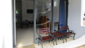 A room with a glass door leading to a balcony with two wooden benches. - Hotel Pantes (Plaosan)