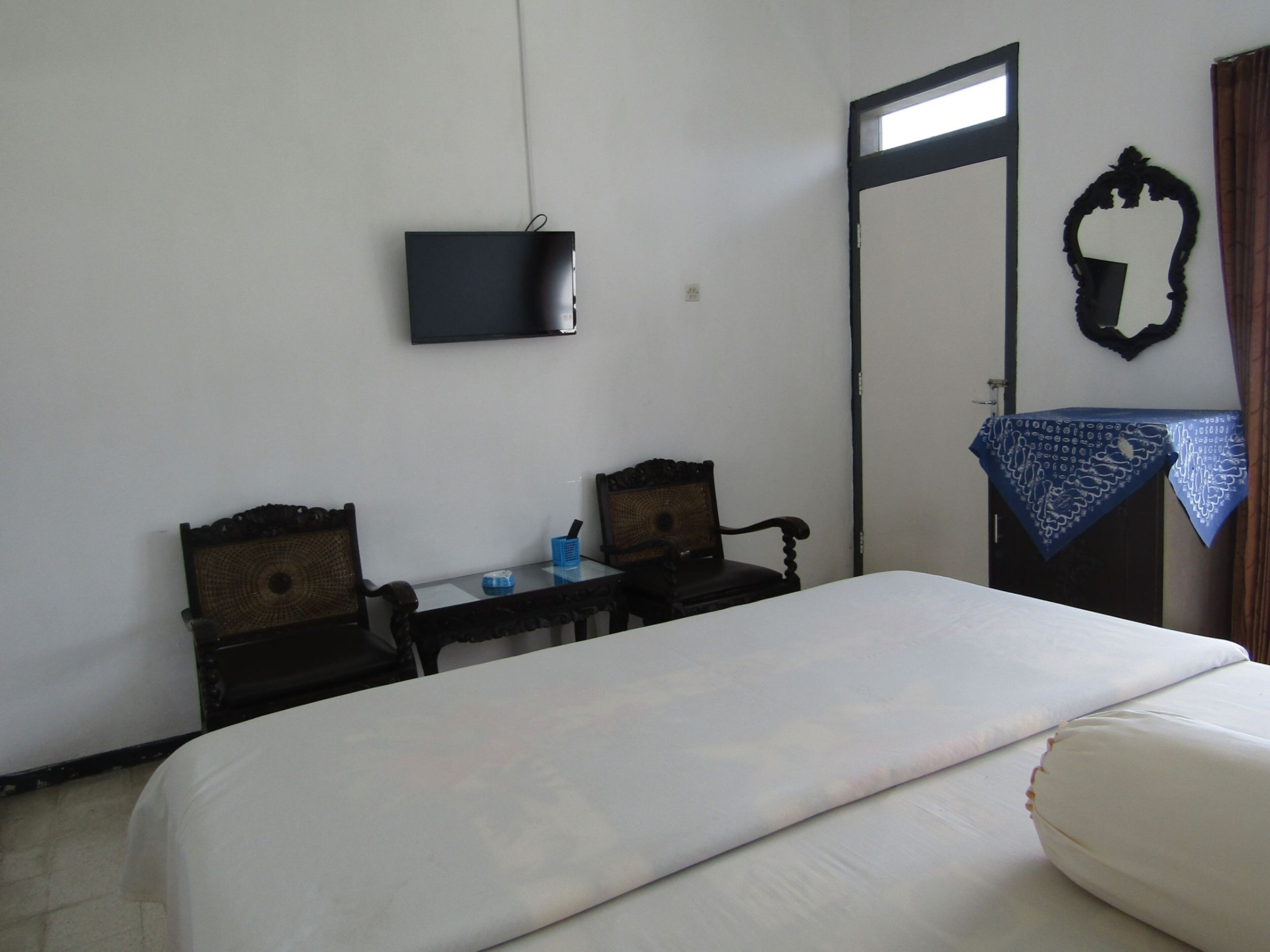 Habitación de hotel con cama, escritorio, dos sillas, televisión en la pared y puerta con espejo.