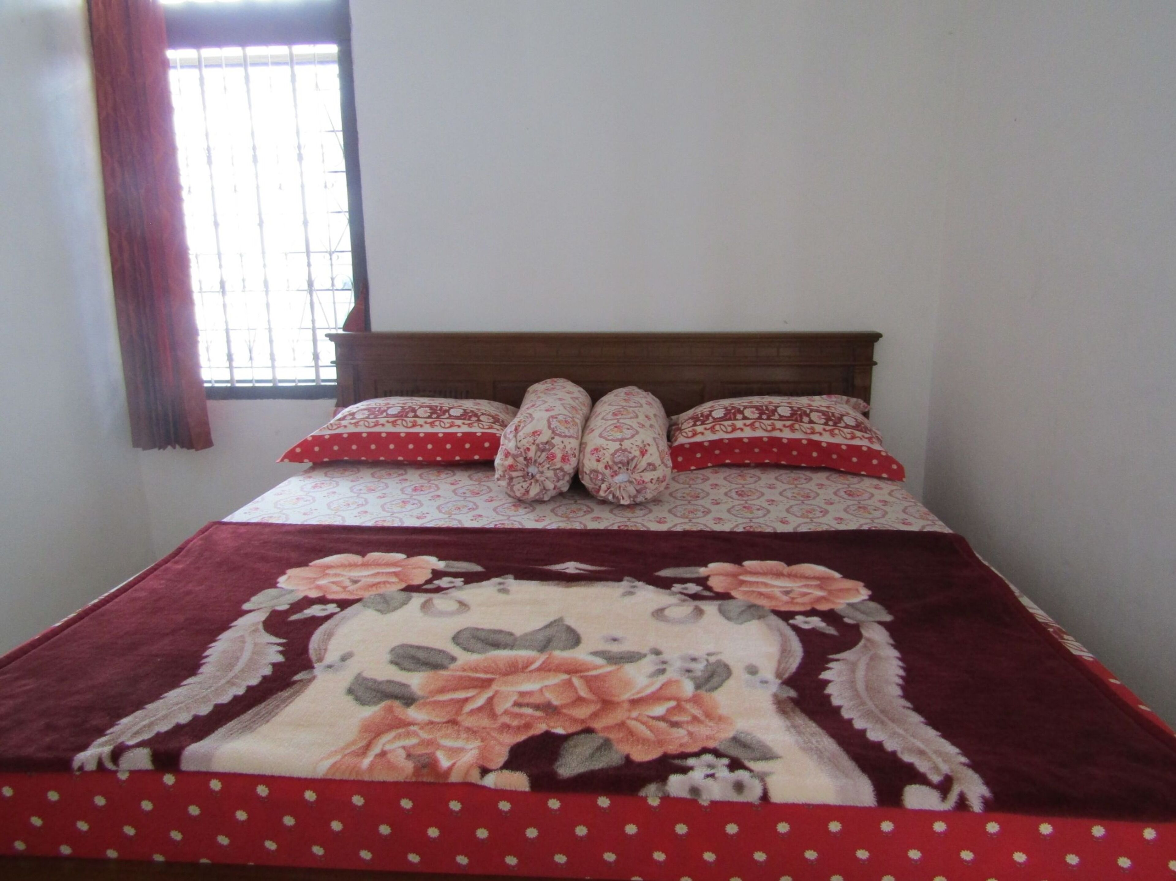 A bed with a floral bedspread, two pillows, and a wooden headboard.