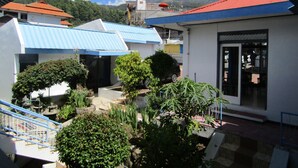A courtyard with multiple buildings, a staircase, and a view of mountains. - Hotel Pantes (Plaosan)