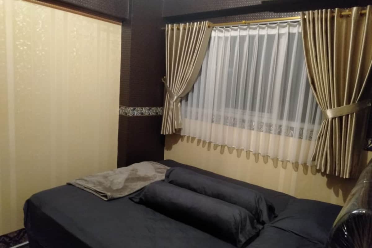 A room with a bed, curtains, and a window.