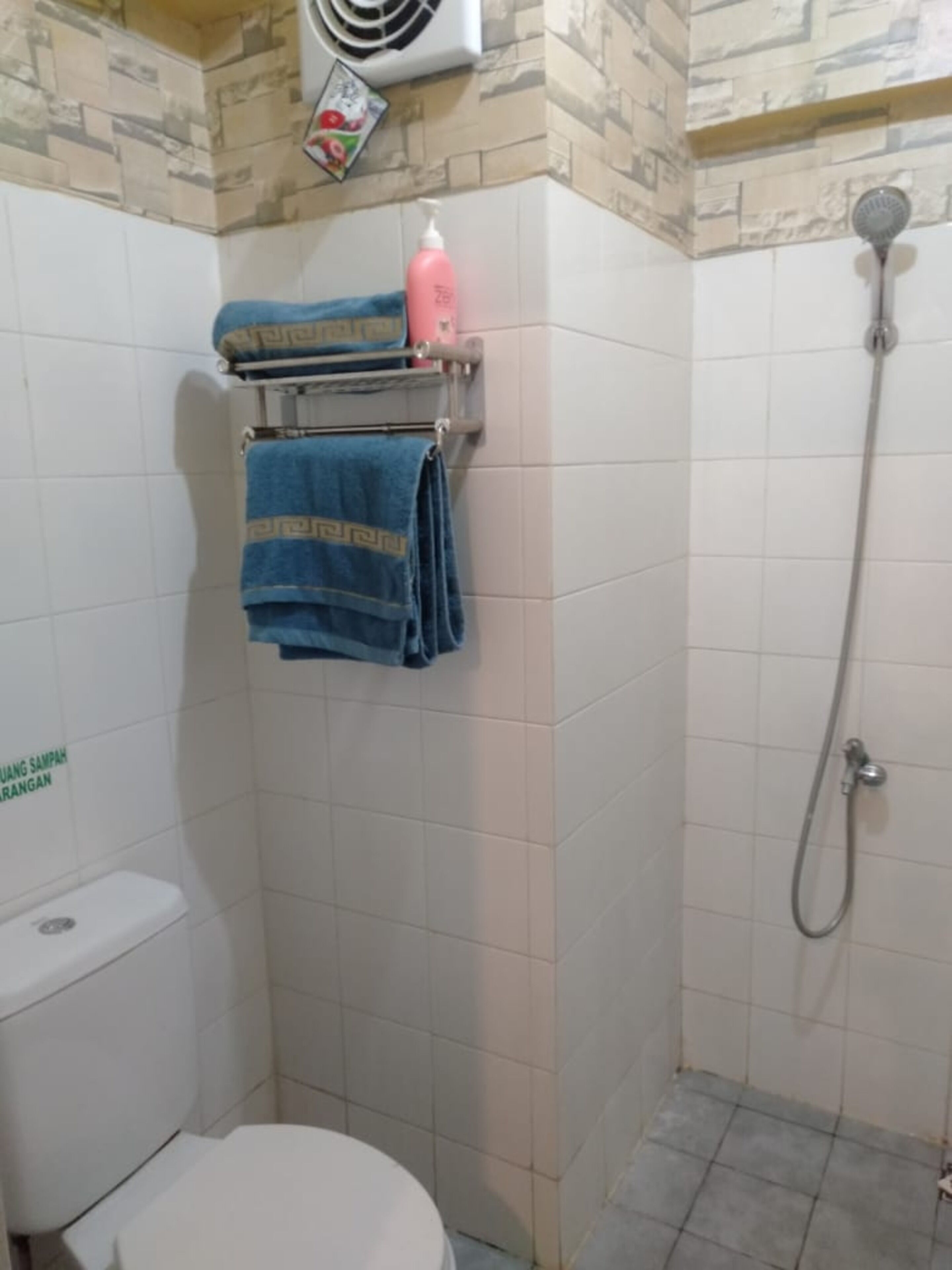 A bathroom with a toilet, a shower, and a towel rack with blue towels.