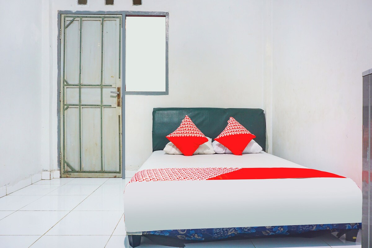 A bed with a white and red patterned bedspread, two red pillows with a white pattern, and a green headboard.