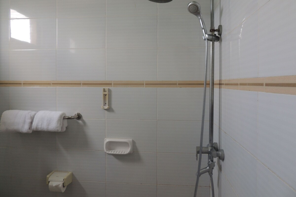 A shower with a handheld showerhead, a handheld shower attachment, and a wall-mounted faucet.