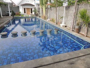 A swimming pool with blue tiles, surrounded by a concrete deck and potted plants. - Cassa Mia Villa 1 (Sleman)