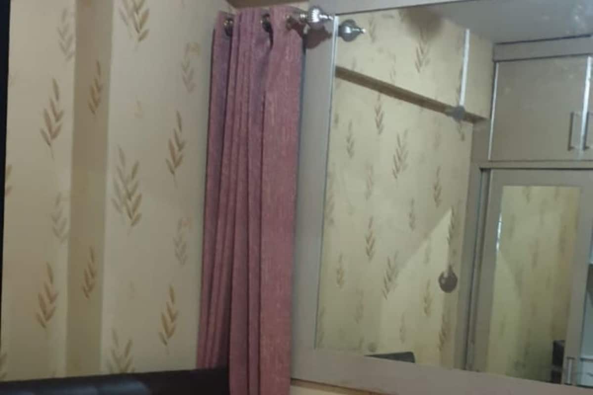 A bedroom with a bed, a window with a curtain, and patterned wallpaper.