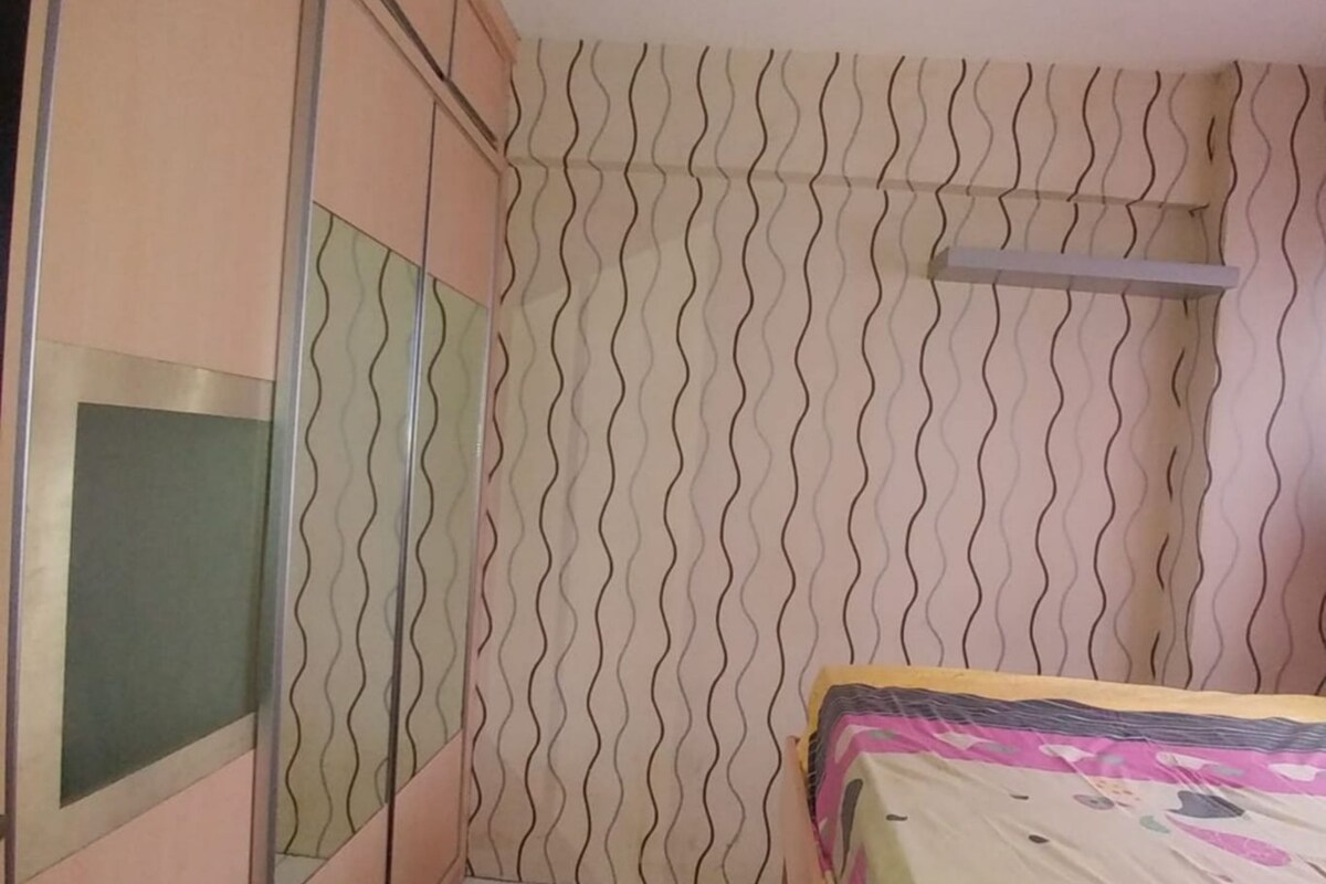 Un dormitorio con cama, armario y papel tapiz estampado.