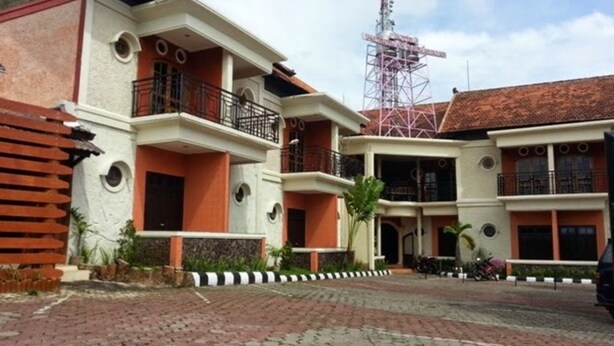 A multi-story building with a central courtyard, featuring balconies and a telecommunications tower in the background. - Hotel Palereman Soerabaia (Batu)