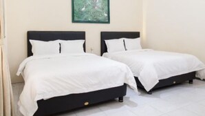 Two single beds with white bedding in a room with a green framed picture on the wall. - Hotel Palereman Soerabaia (Batu)