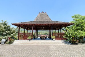 A traditional pavilion with a tiled roof, surrounded by a paved area and potted plants. - Balkondes Duta Menoreh (Borobudur)