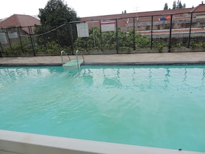 A swimming pool with a metal fence and a ladder. - Studio Room at V Apartment (Depok)