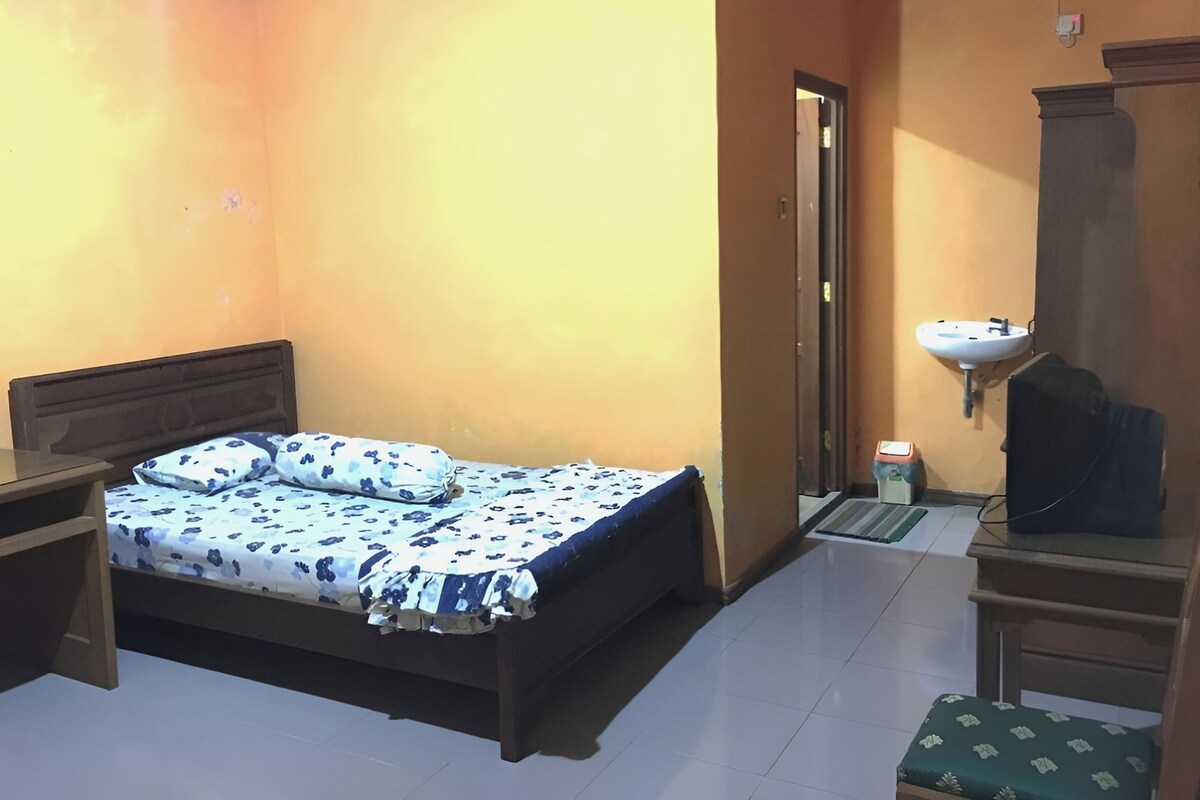 Un dormitorio con cama, mesita de noche, cómoda, espejo y lavabo.