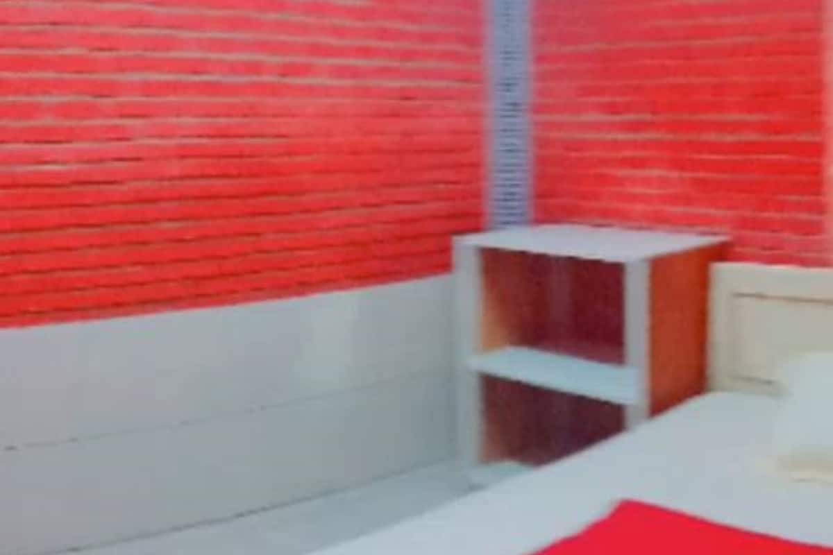 A room with a bed, a white headboard, and a red wall.