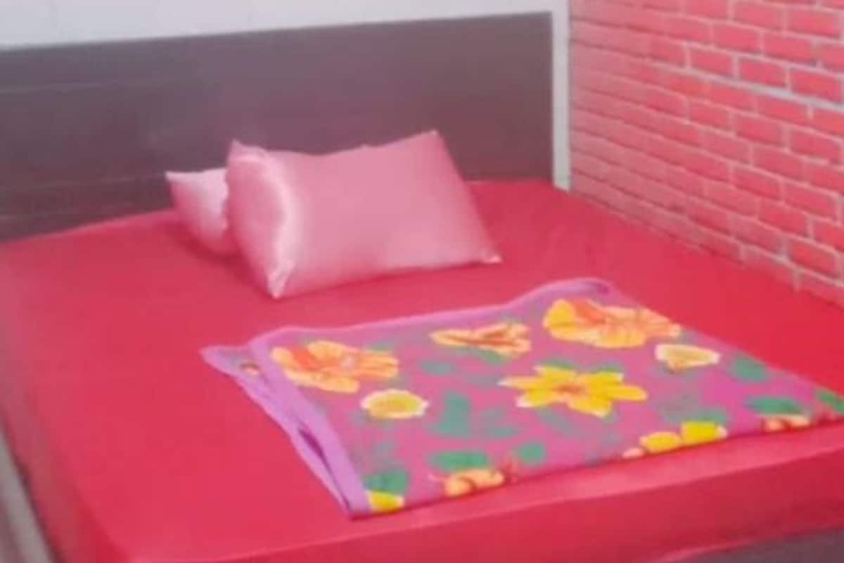 A bed with a red mattress and a floral-patterned blanket.
