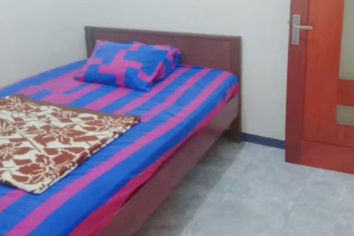 A single bed with a striped bedspread and a patterned throw.