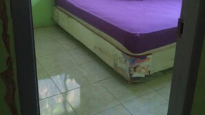 Una habitación con una cama, paredes verdes y una ventana con cortinas.