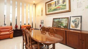 A dining area with a wooden table and chairs, a sofa, and framed artwork on the wall. - Soerabaja Place Guest House (Surabaya)