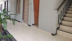 Un pasillo con una escalera, una puerta de madera y un letrero que indica una zona accesible para sillas de ruedas.