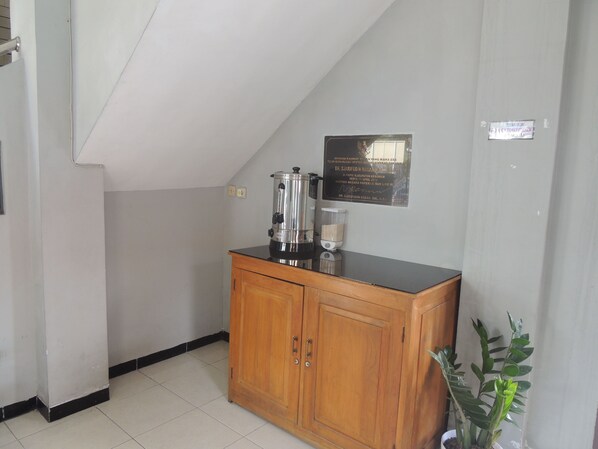 Una kitchenette pequeña con cafetera, licuadora y un armario.