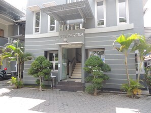 Entrada de un hotel de diseño moderno, una escalera que conduce a la entrada y varias palmeras alrededor.