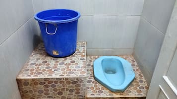 Un baño pequeño con un cubo y un inodoro, ambos azules.