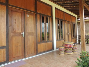 A wooden building with large doors and windows, a tiled floor, and decorative pottery. - Balkondes Karanganyar (Pottery Academy) (Borobudur)