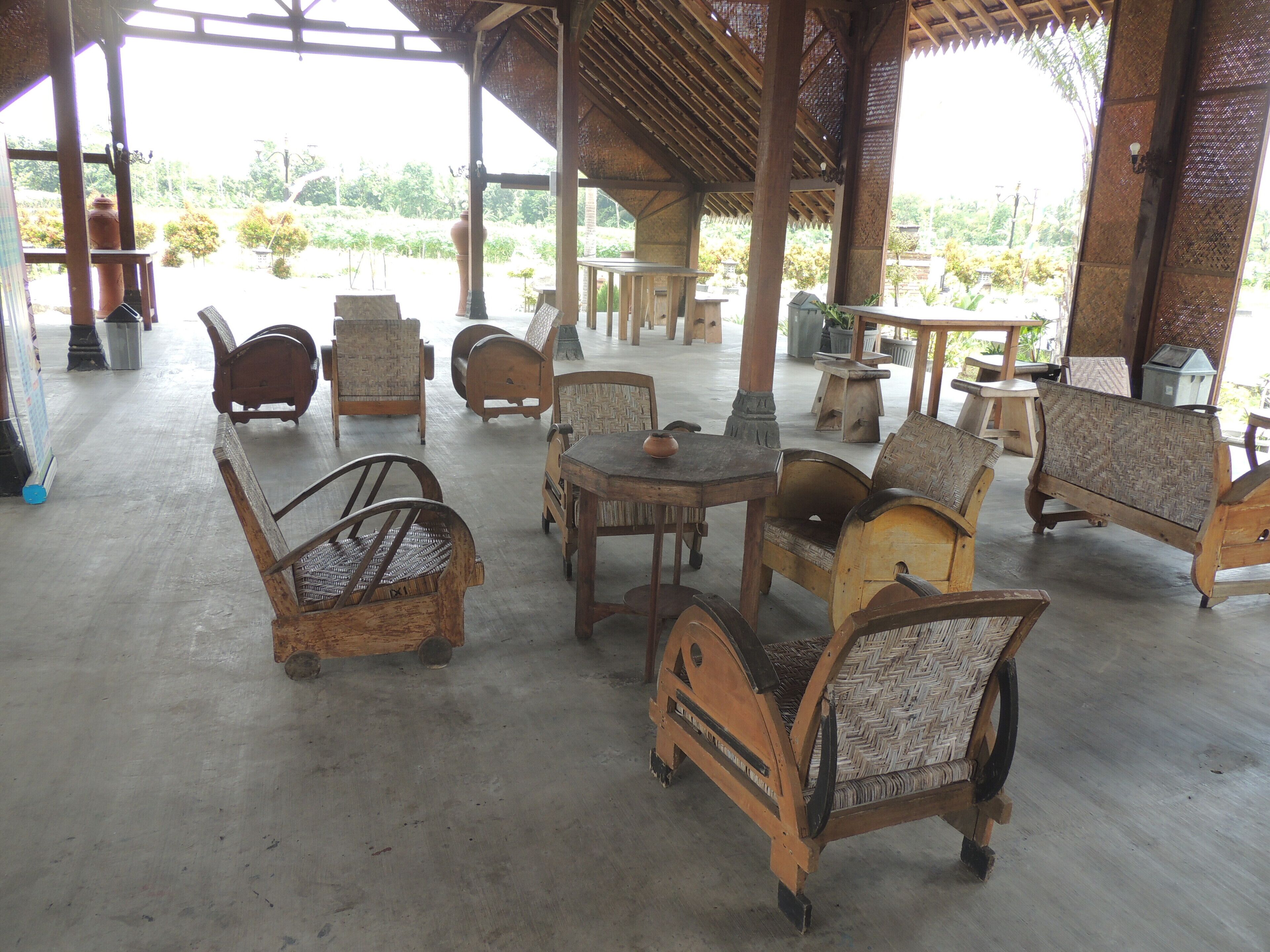An outdoor seating area with wooden furniture and a thatched roof.