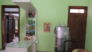 A compact kitchen with a refrigerator, a glass-top island, and shelves with various bottles. - Avicenna 2 Guesthouse (Demangsari)