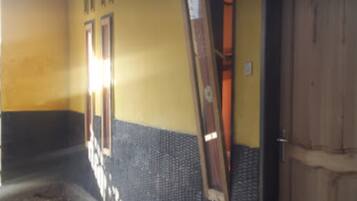 A corridor with a tiled wall, a wooden door, and a metal rack.