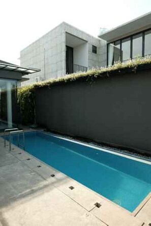 A modern building with a swimming pool, a covered area, and a concrete deck. - Group Villa Luxury (Batu)