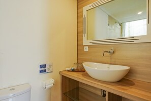Une salle de bain avec un lavabo blanc, un miroir et des toilettes.