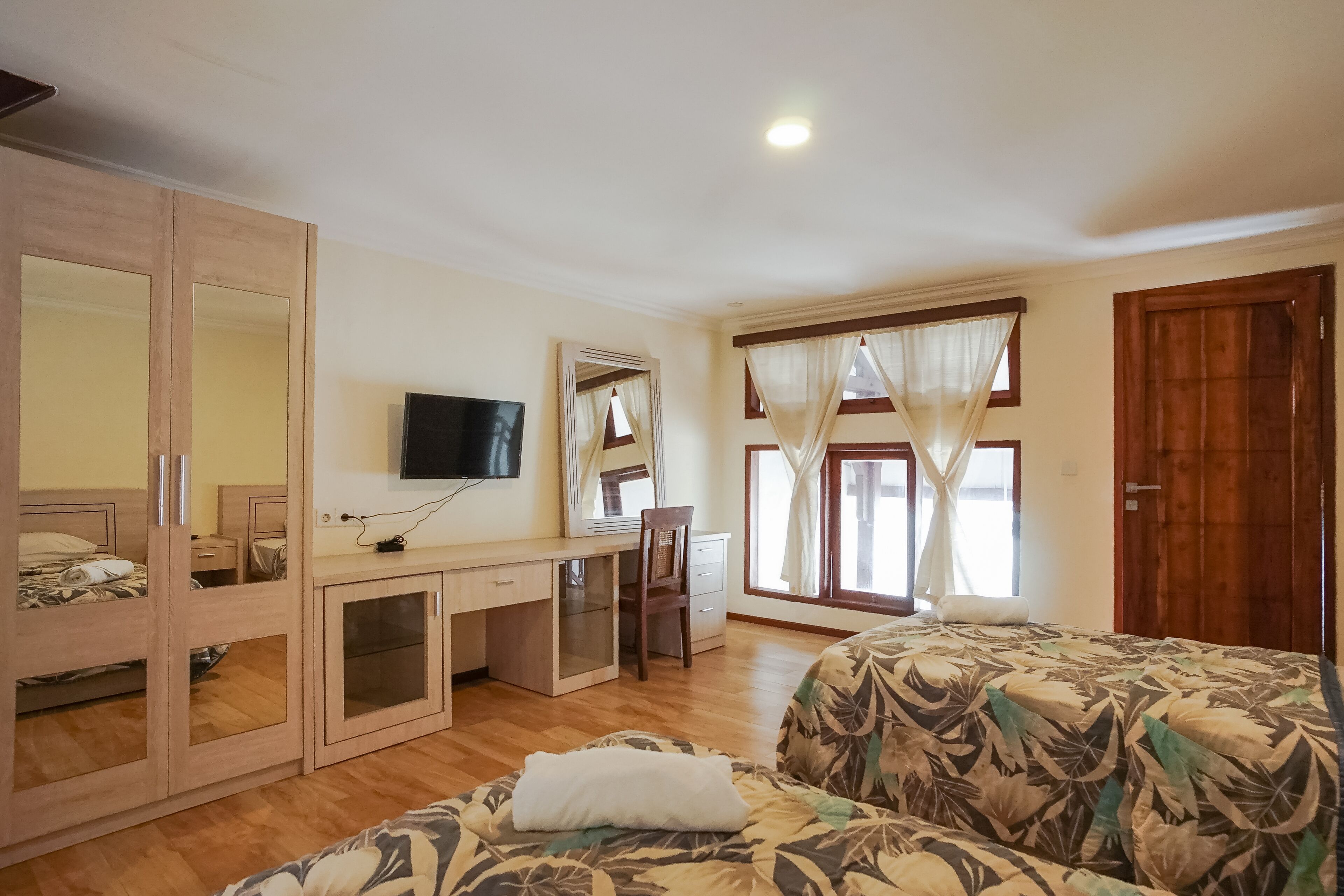 A bedroom with a bed, a desk, a wardrobe, and a television.